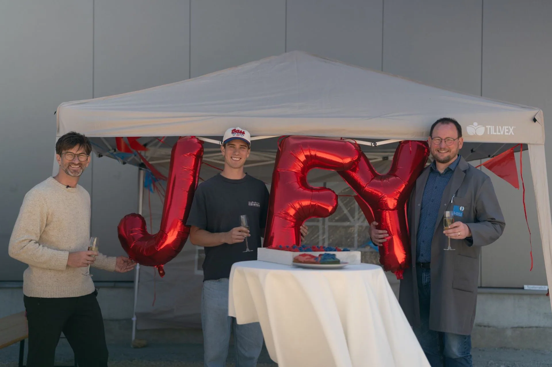 I-H&S-team viert de nieuwe JFY-samenwerking met rode JFY-ballonnen en champagne voor de hal