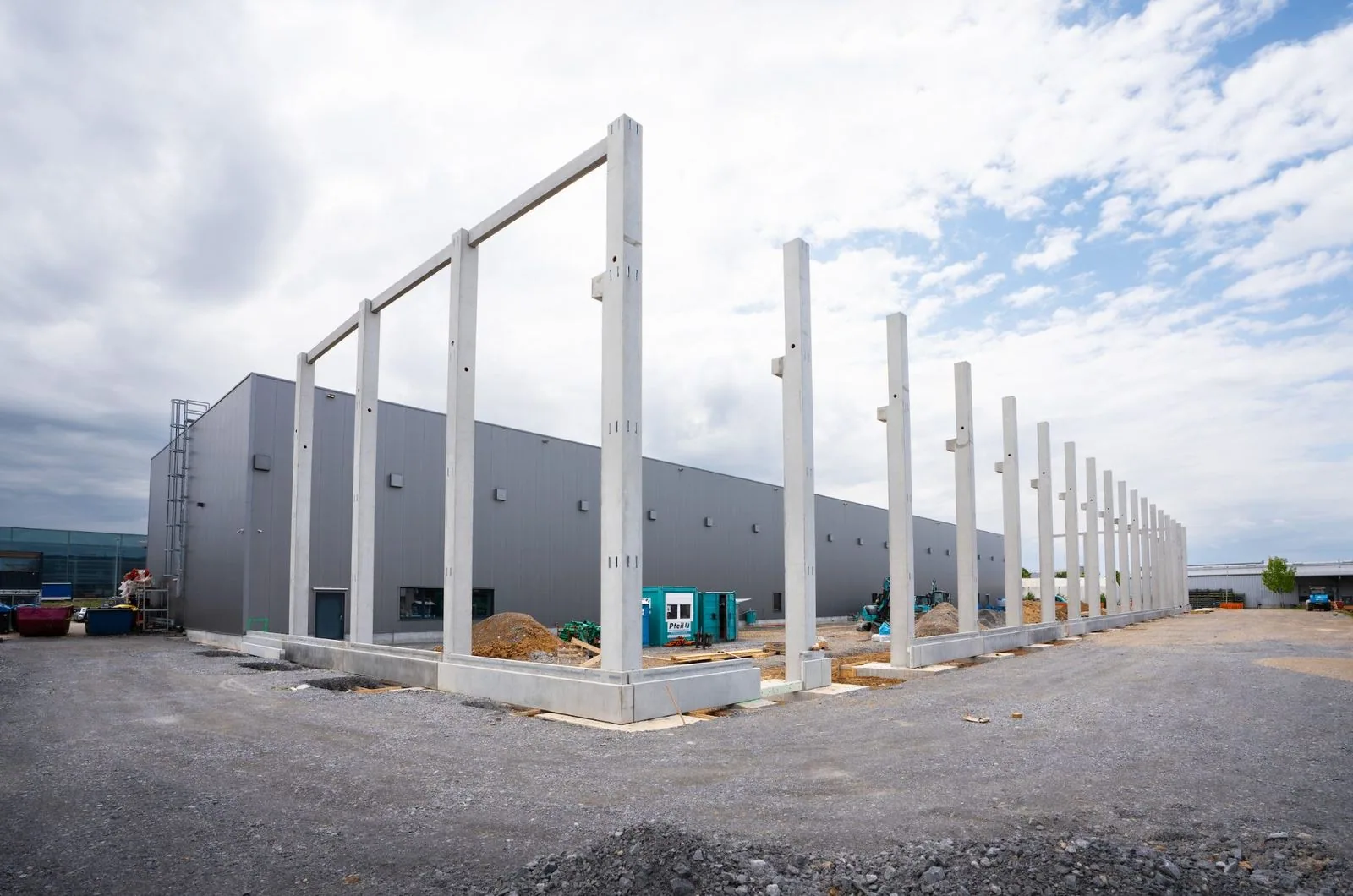 Geplaatste betonpilaren van de nieuwe JFY-showroom naast de bestaande hal